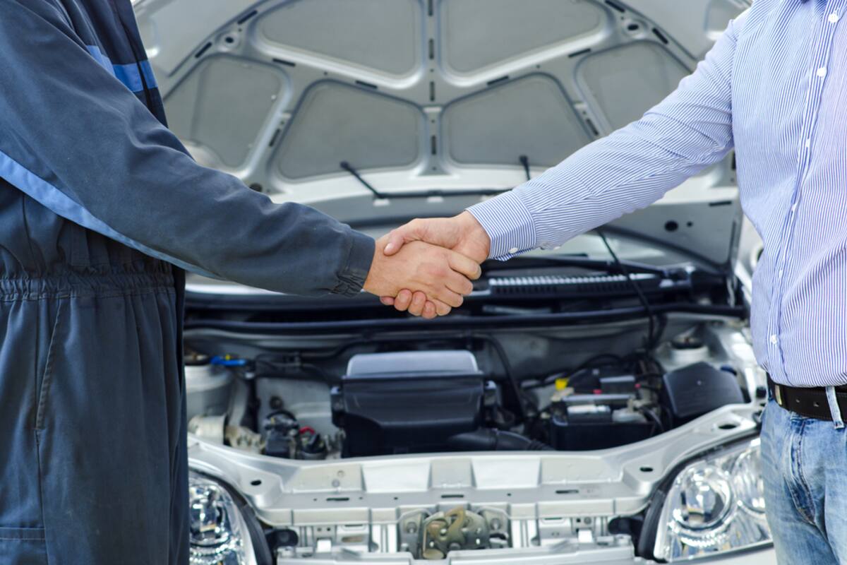 Technician and customer shaking hands over an open hood