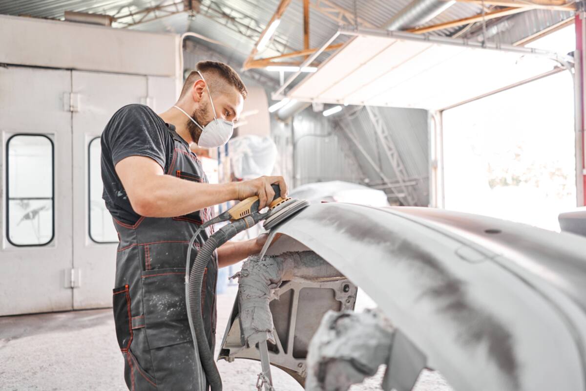 Technician working on a car body panel in a shop