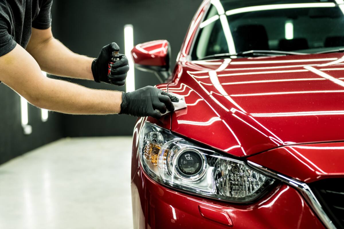 Gloved hand applying a coating to a red car