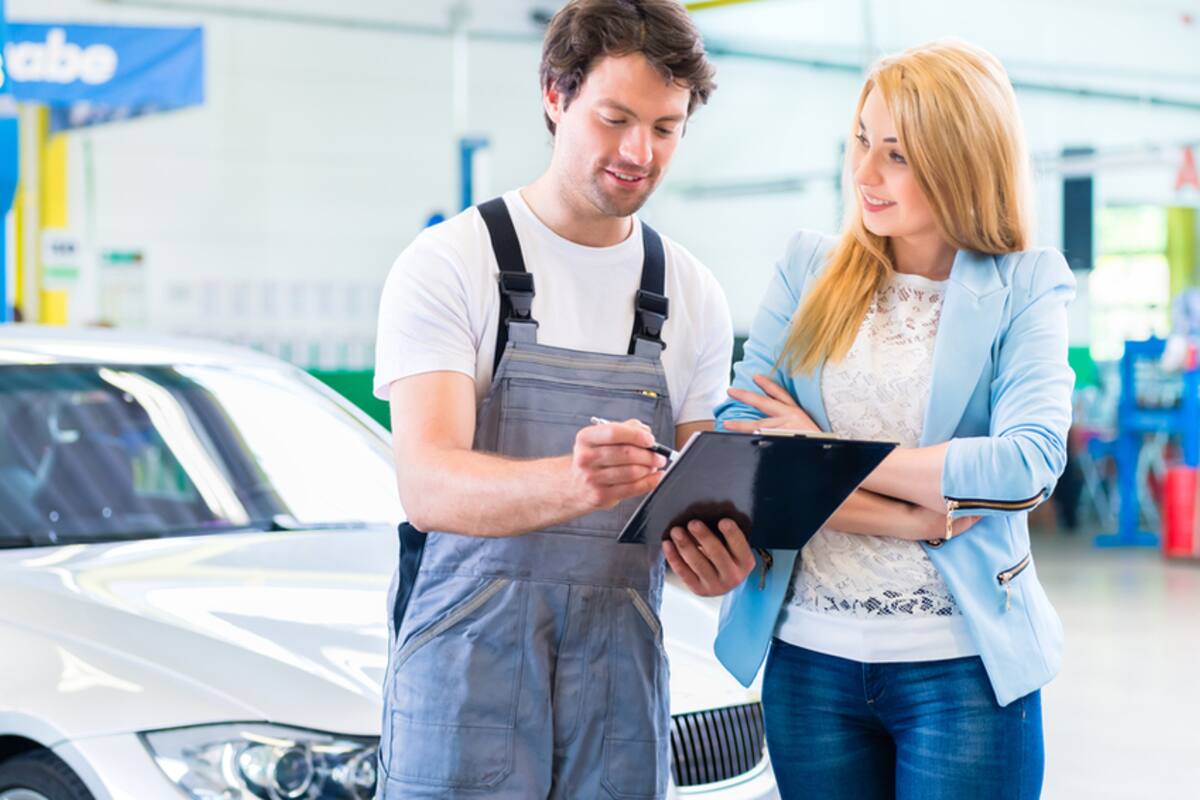 Technician reviewing paperwork with a customer in a service bay
