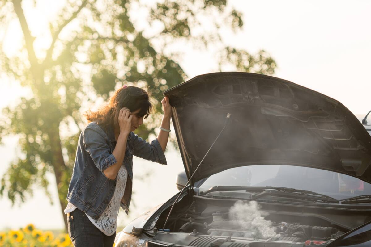 Driver beside a car with steam rising from the hood