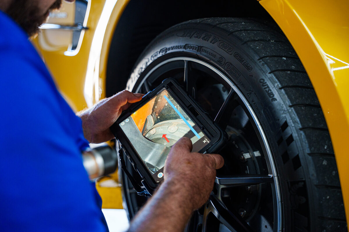 Technician photographing tire tread on a tablet during an inspection