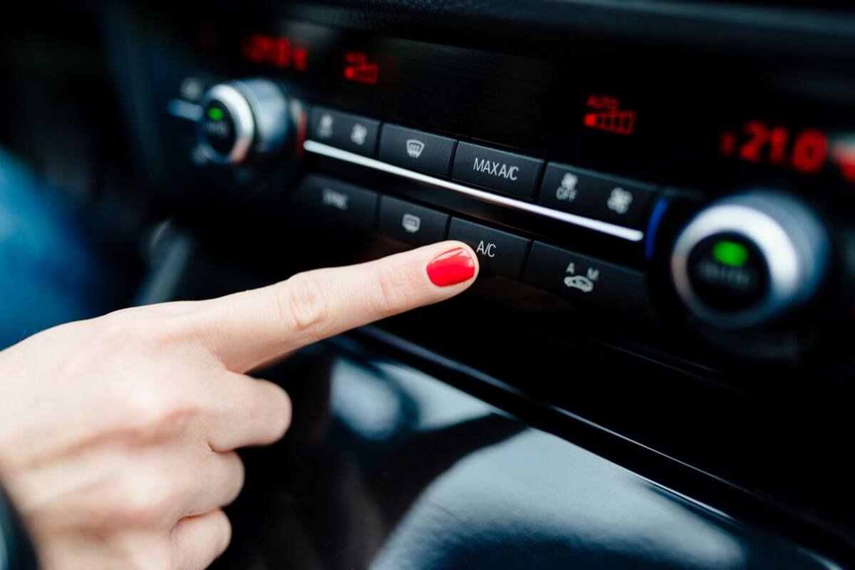 Finger pressing the air conditioning controls on a dashboard