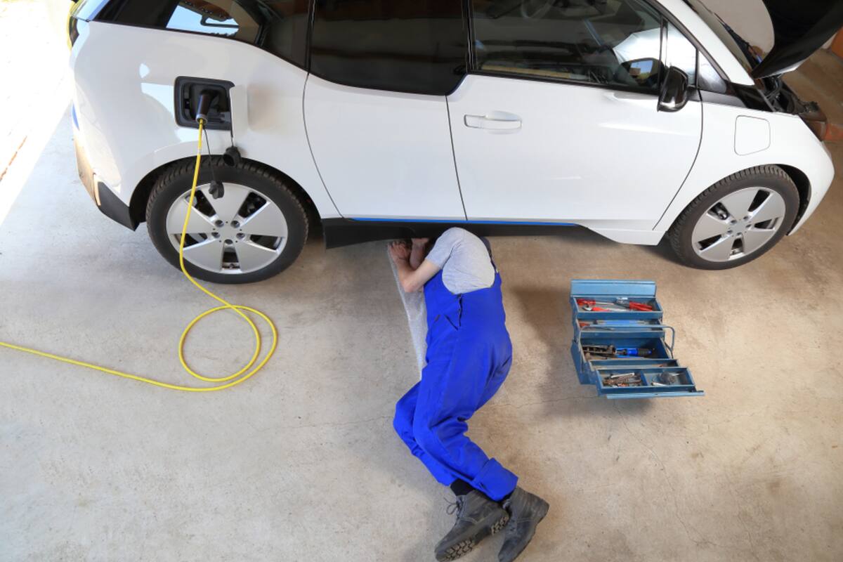 Technician servicing a plugged-in electric car