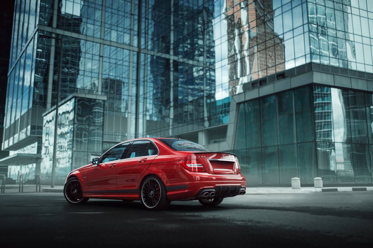 Red Mercedes parked beside glass office buildings