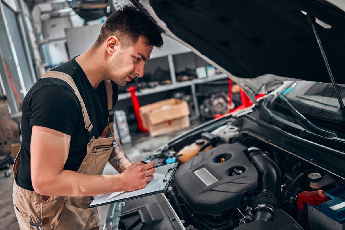 Technician inspecting an engine with a clipboard