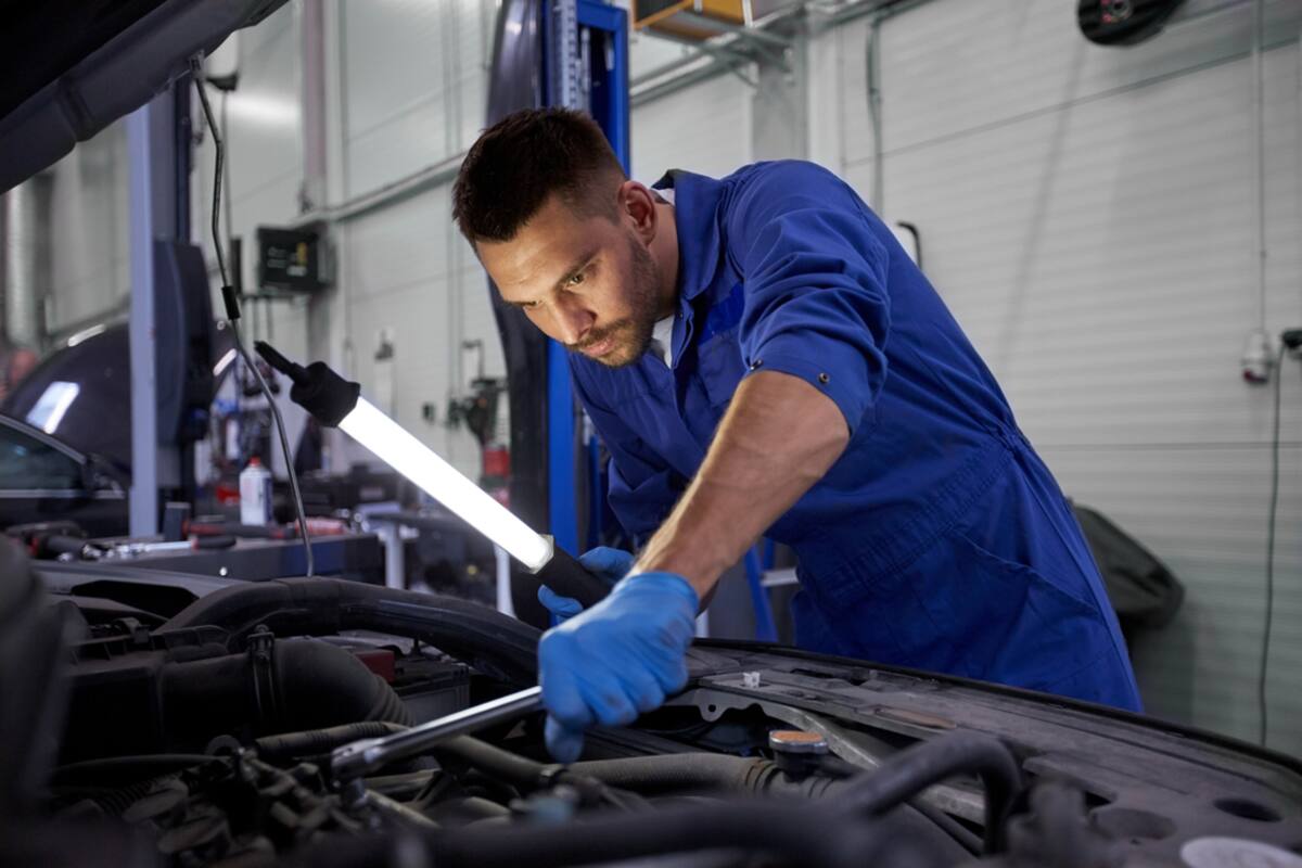 Technician working beneath a raised car