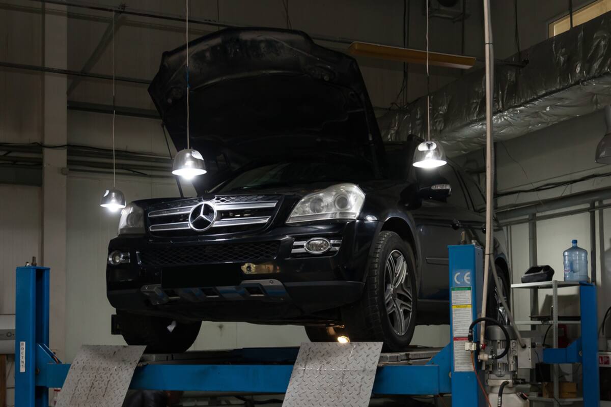 Black Mercedes raised on a workshop lift