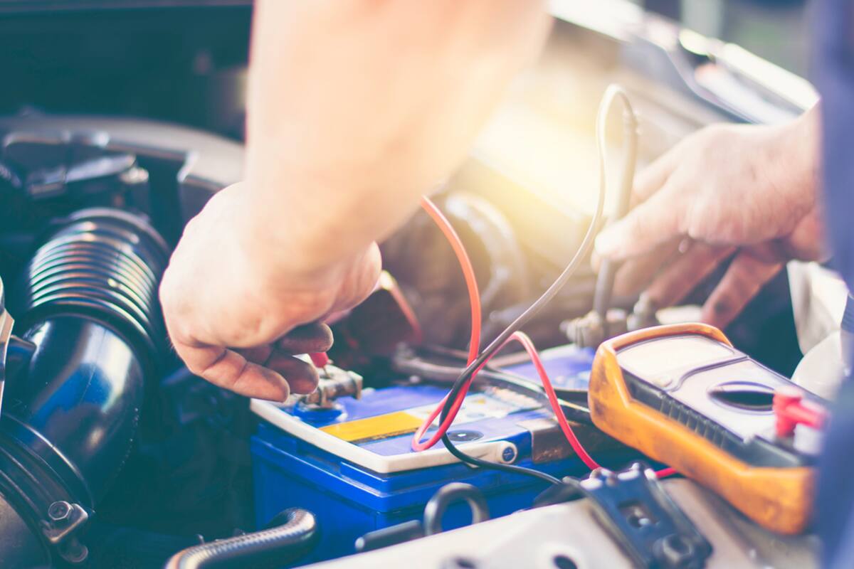 Technician testing a car battery with a multimeter