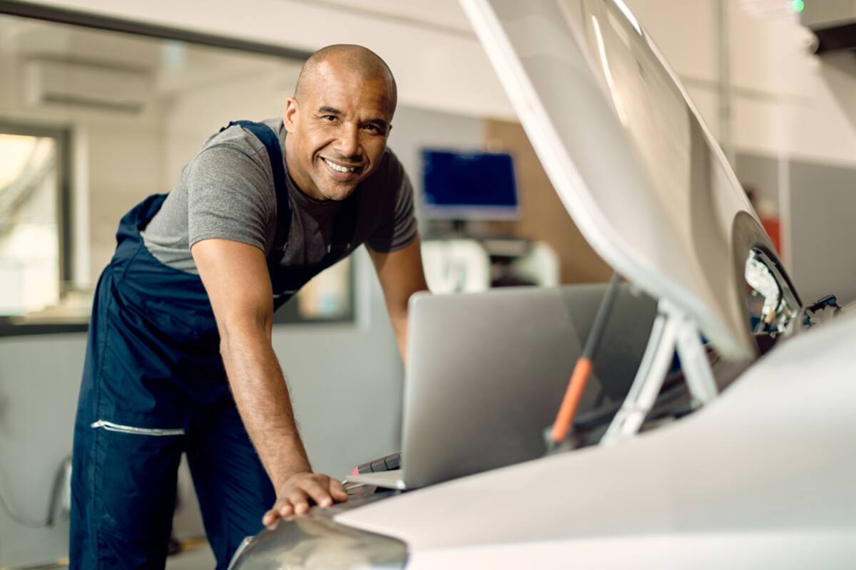 Technician using a laptop beside an open hood