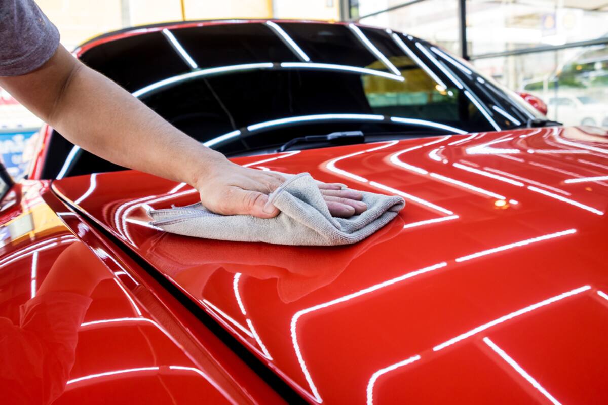 Hand polishing the hood of a red car