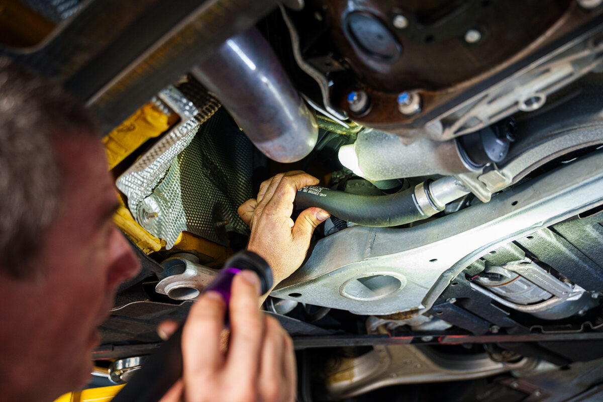 Technician inspecting the drivetrain from underneath a raised car
