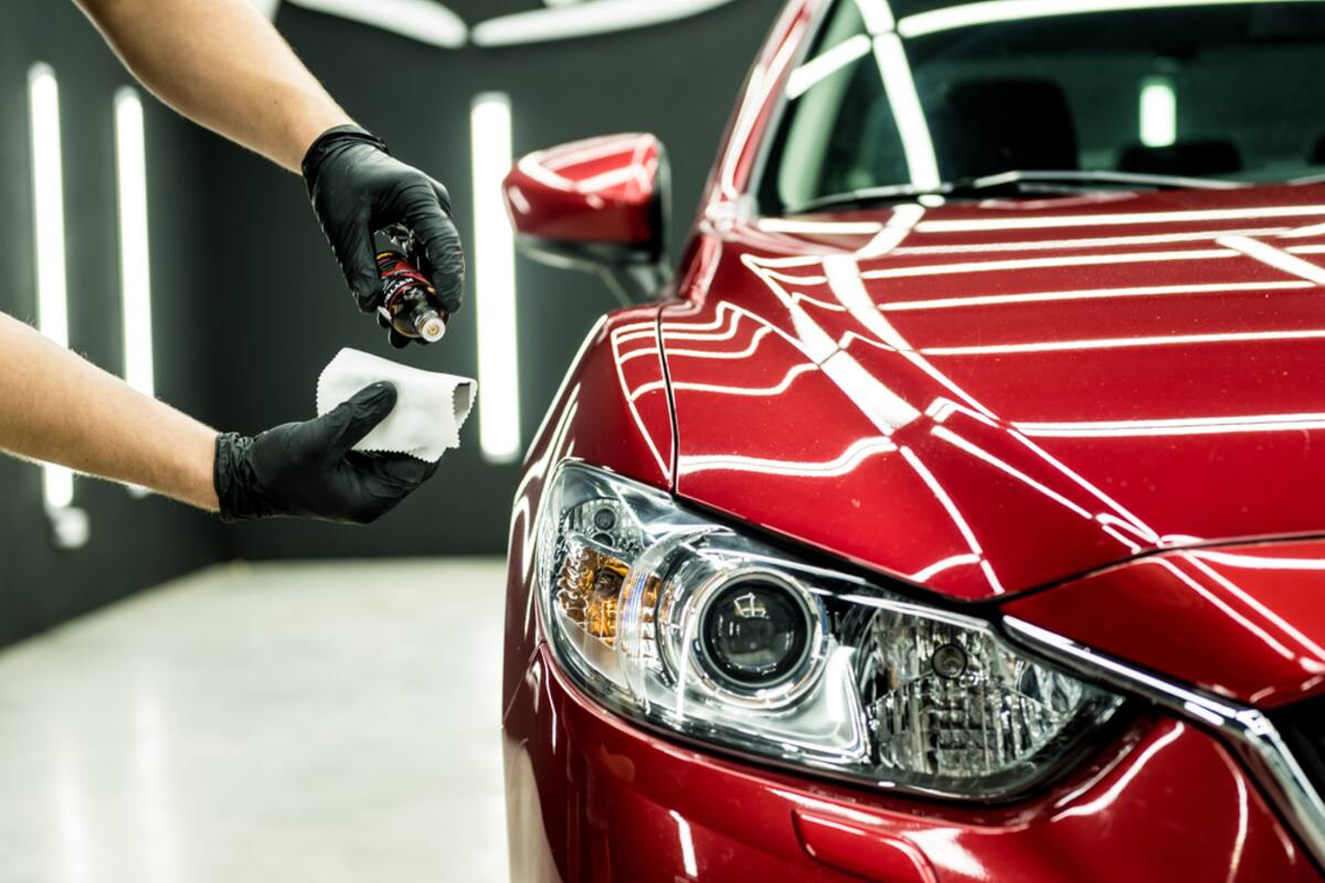 Gloved hands applying a ceramic coating to a red car