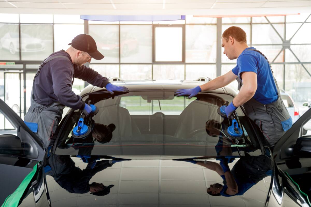 Two technicians fitting a windshield