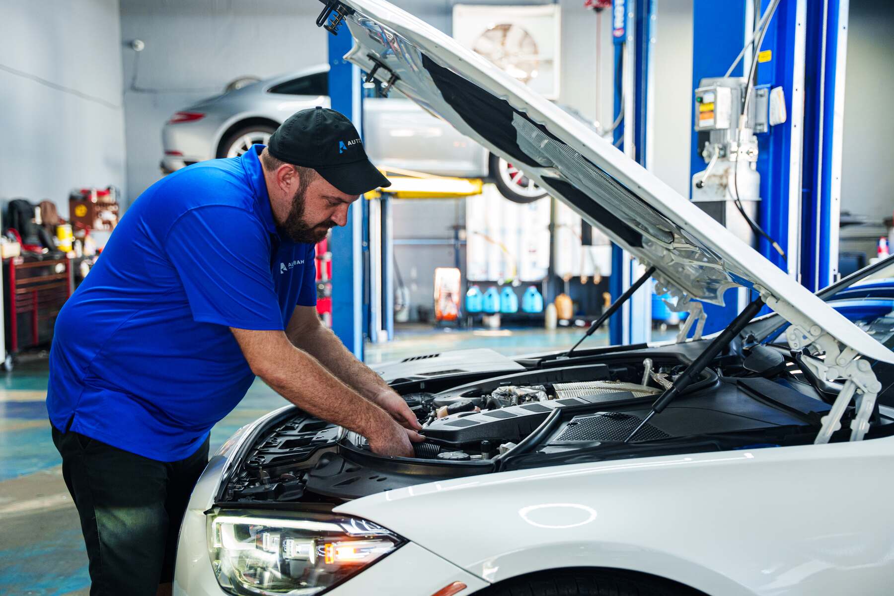 An Autobahn technician working under the hood of a BMW