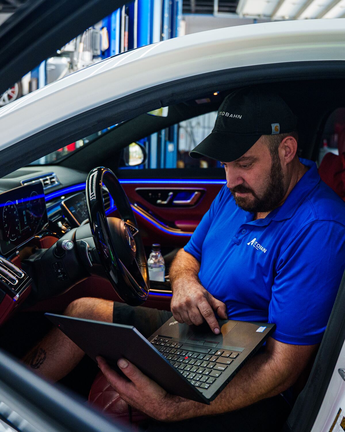 An Autobahn technician on a laptop in the driver&rsquo;s seat of a Mercedes-Benz