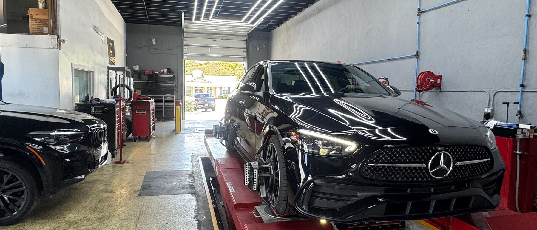 A black Mercedes-Benz C-Class on the alignment rack at Autobahn Auto Center