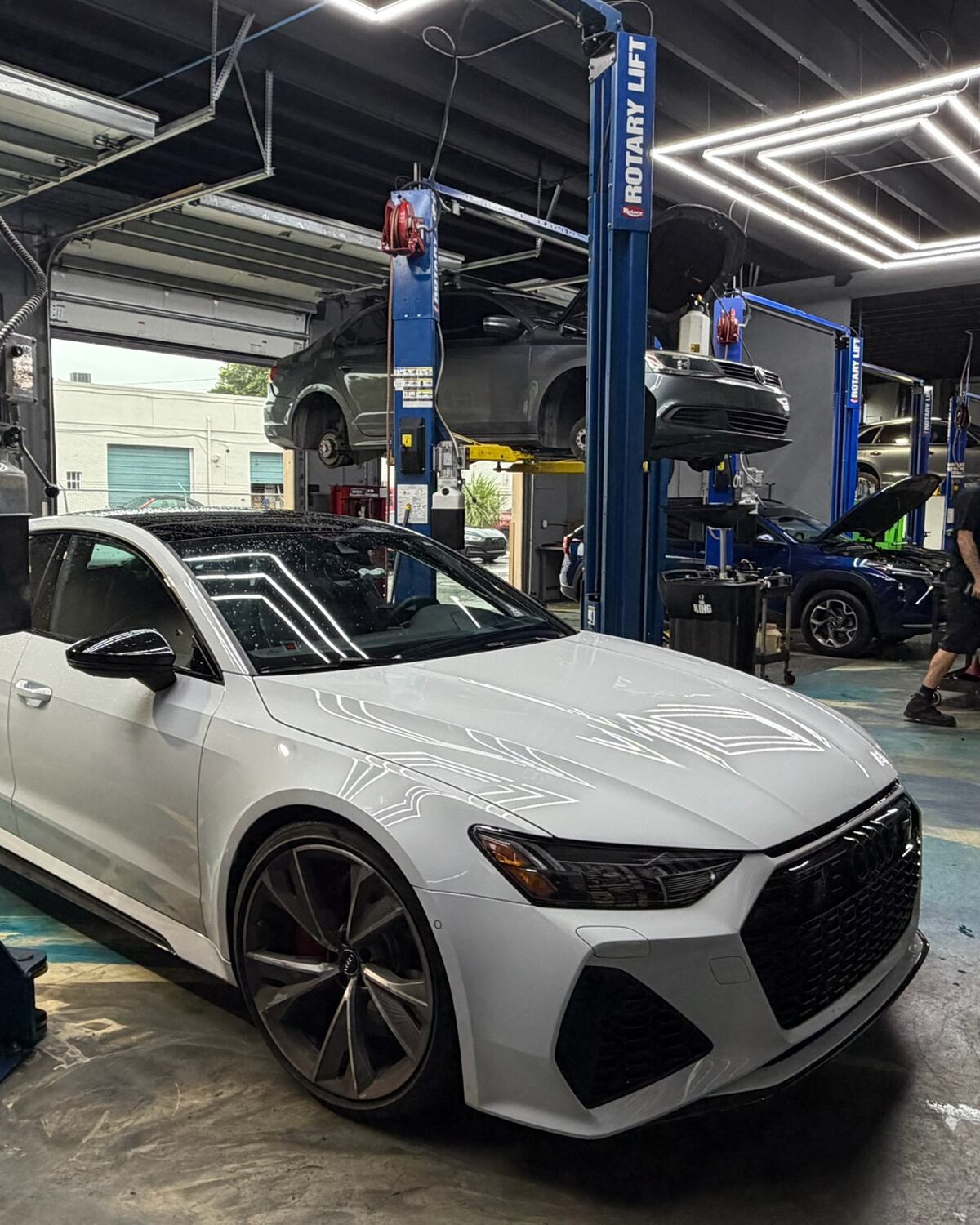 A white Audi RS 7 between the lifts at Autobahn Auto Center