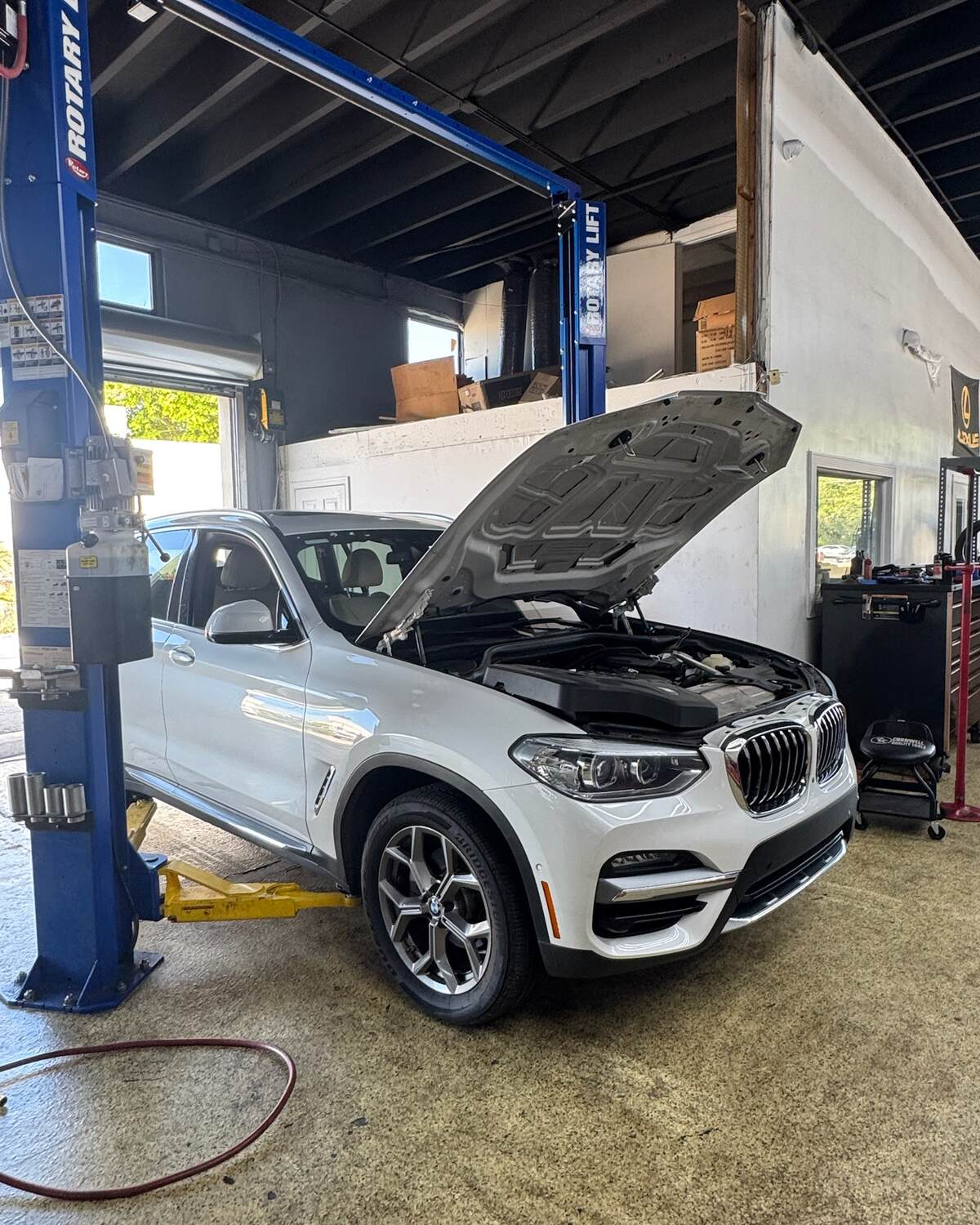 A white BMW X3 with the hood open at Autobahn Auto Center
