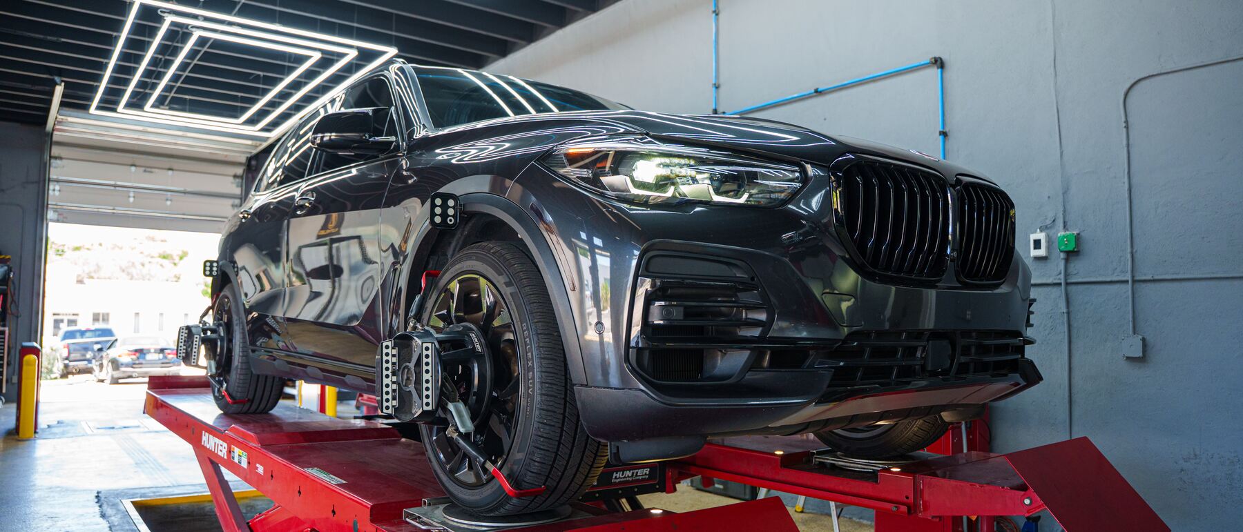 A gray BMW X5 on the alignment rack at Autobahn Auto Center