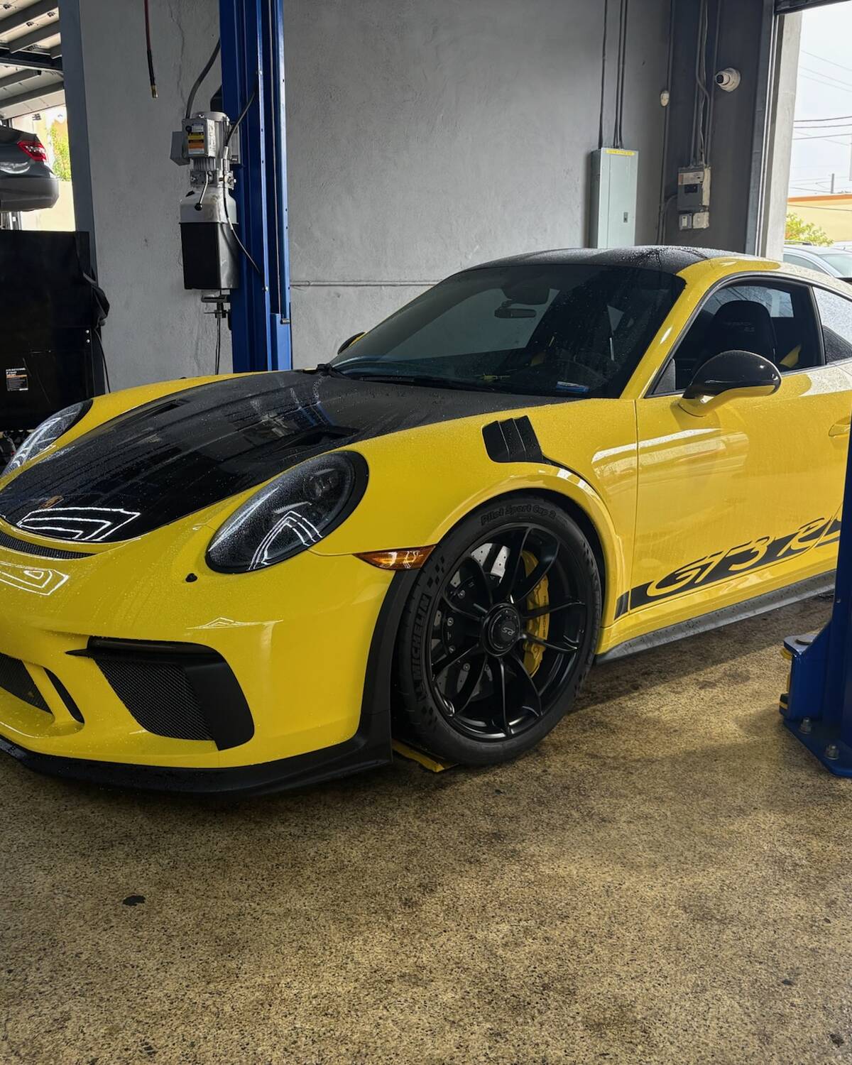 A yellow Porsche 911 in the service bay at Autobahn Auto Center