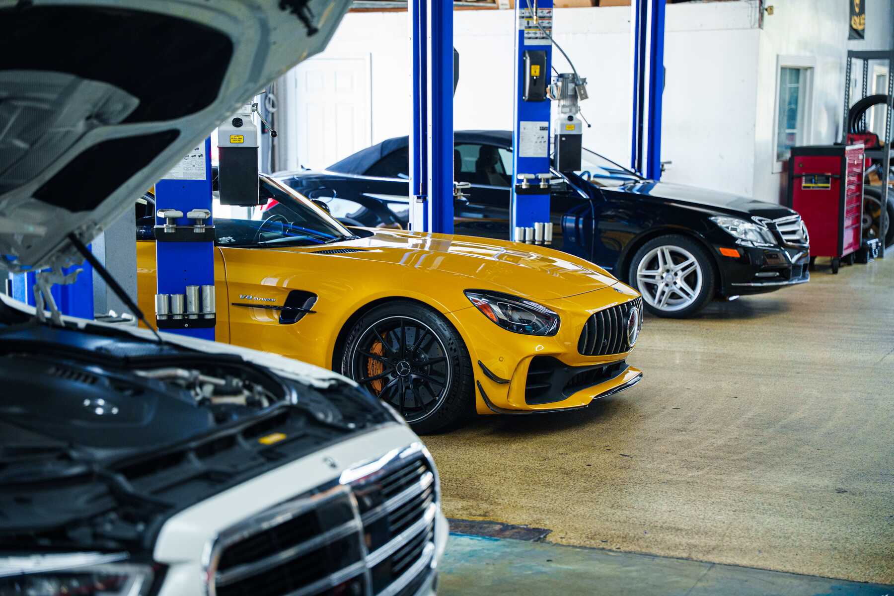 Yellow Mercedes-AMG GT and a black Mercedes in the service bay at Autobahn Auto Center