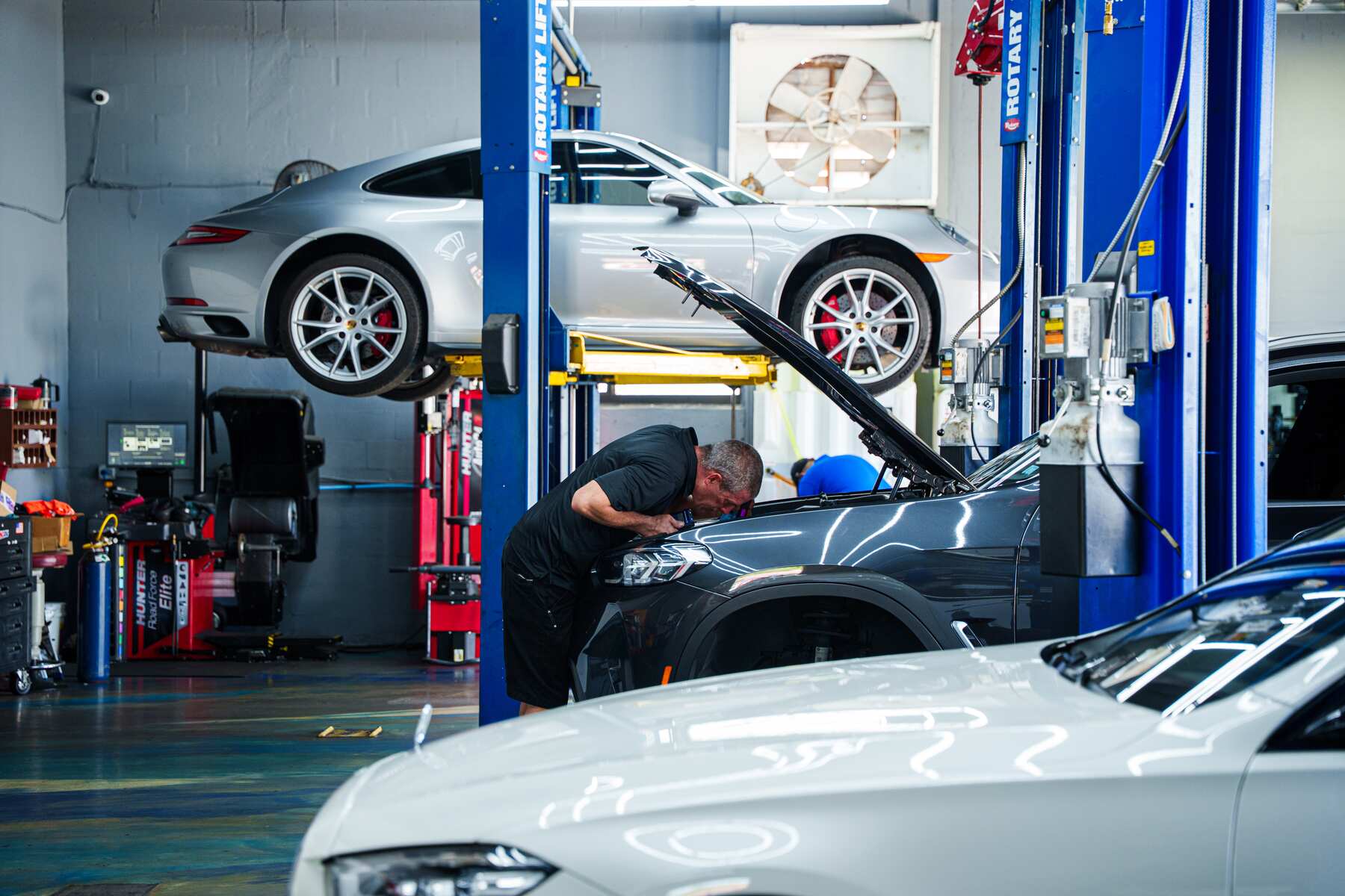 A silver Porsche 911 raised on the lift at Autobahn Auto Center