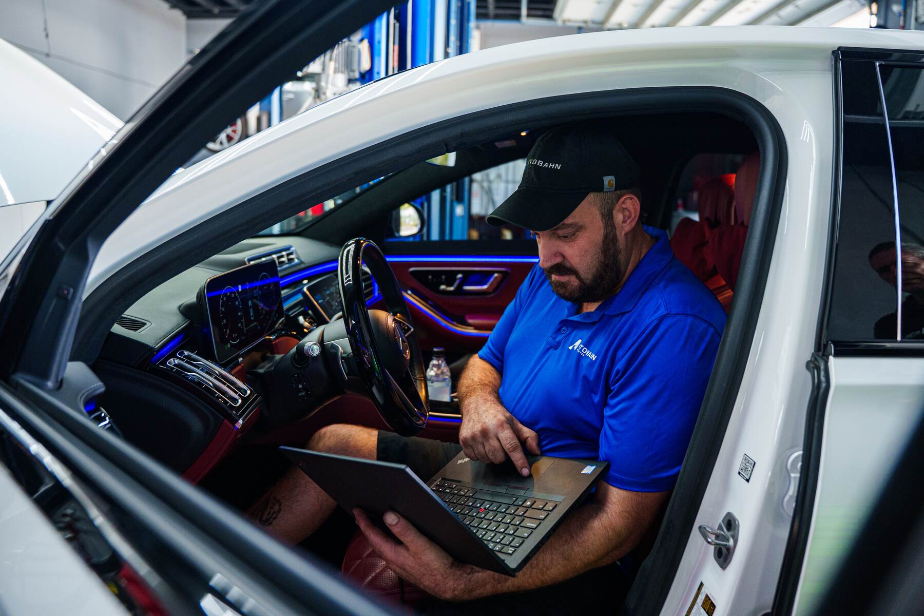 An Autobahn technician running diagnostics from the driver's seat of a Mercedes