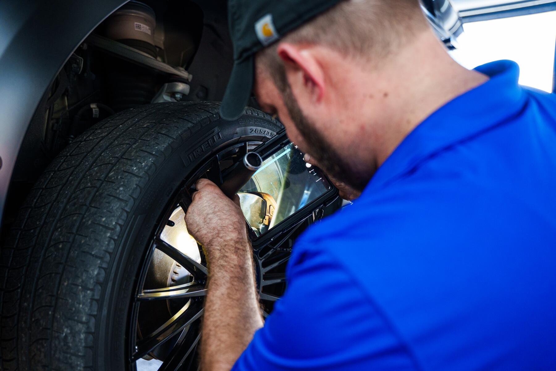 An Autobahn technician working at the wheel of a vehicle on the lift